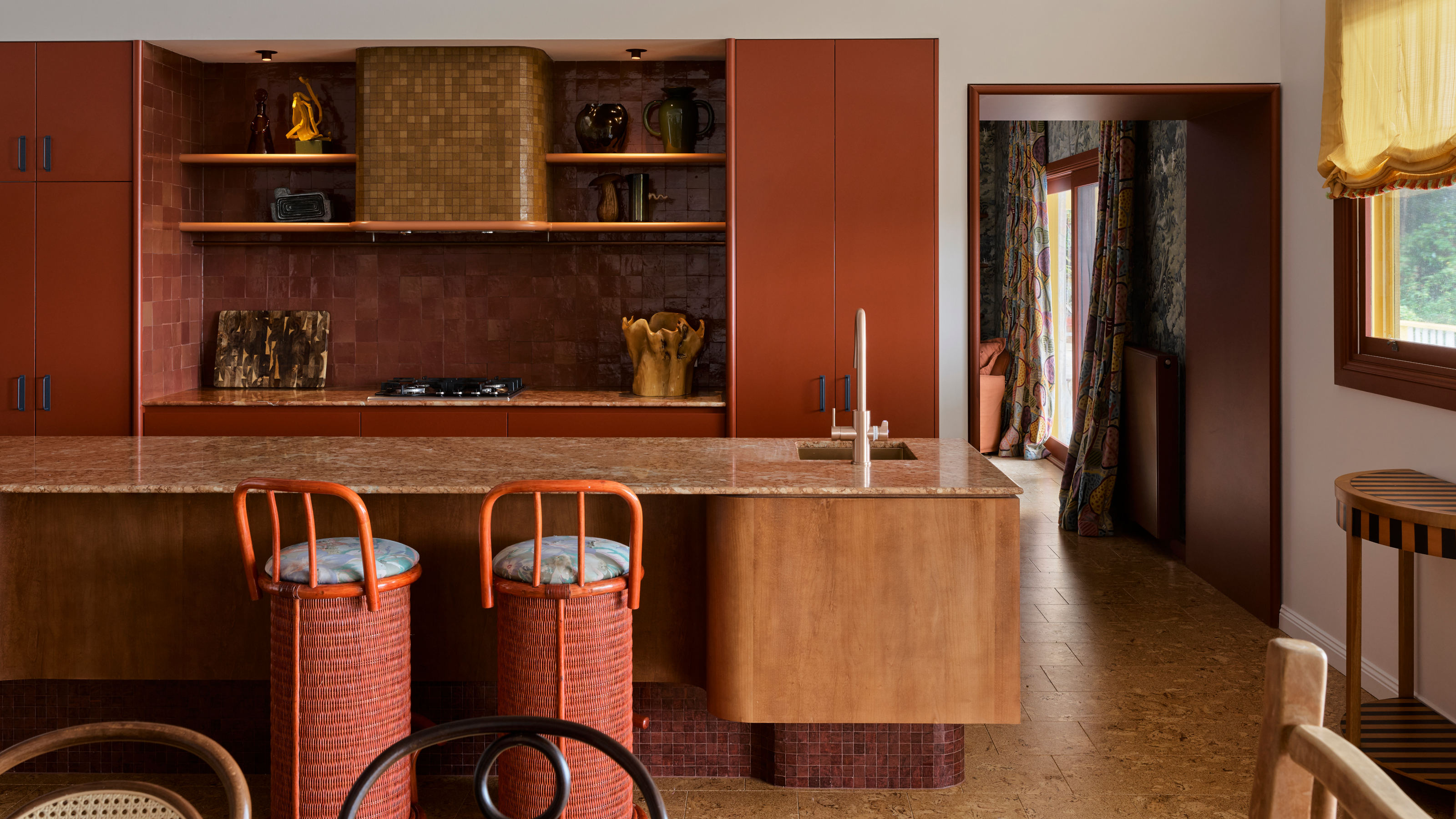 Burned orange kitchen with wood island, brown marble countertop and orange bar stools