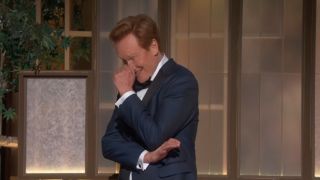 Conan O'Brien laughing and putting his hand to his face at the 2026 Oscars