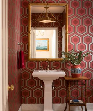 Red and white geometric wallpaper, gold framed mirror