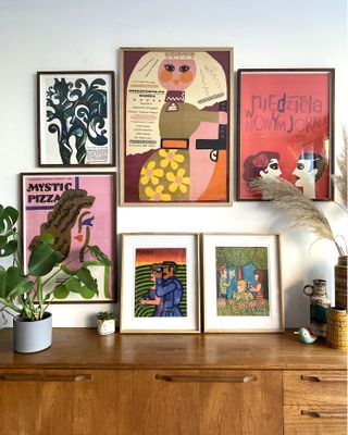 A collection of vintage prints by a sideboard with matching frames