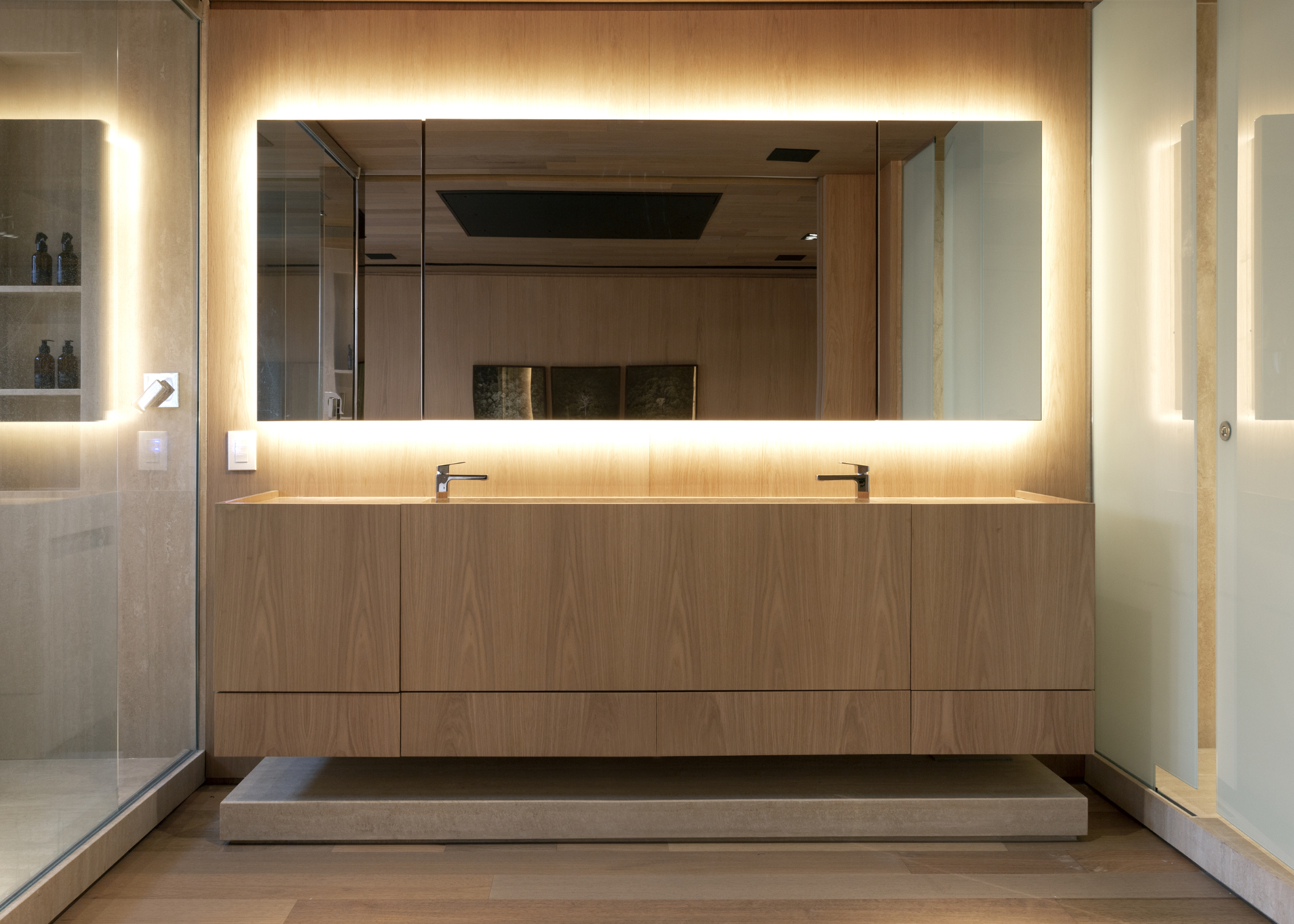 A bathroom with a large backlit mirror above a vanity