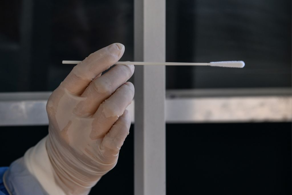 Chinese health worker holds up a swab