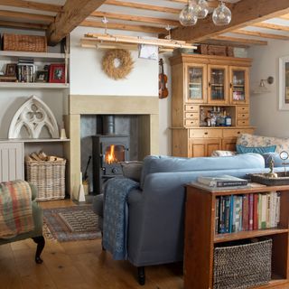 cottage living room with log burner in stone fireplace, ceiling beams and traditional sofas and armchair