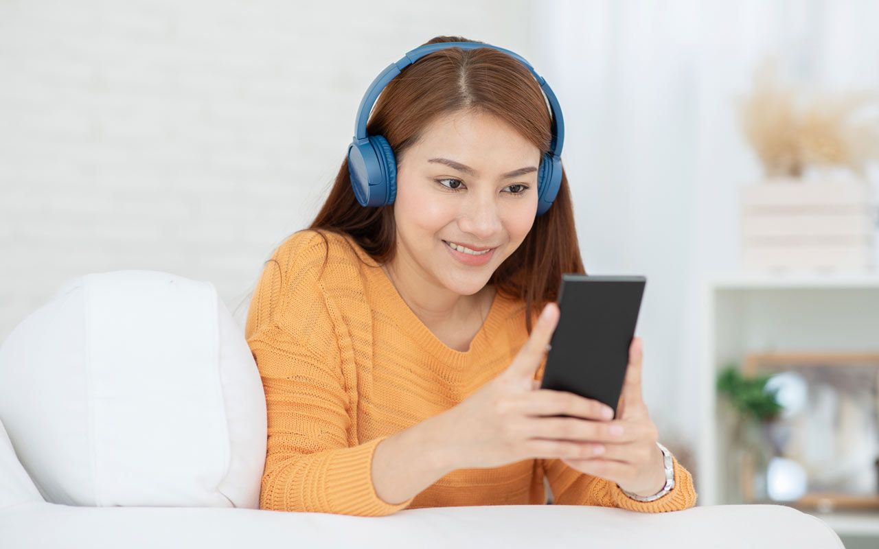 Woman using headphones to listen to phone.