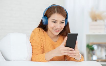 Woman using headphones to listen to phone.
