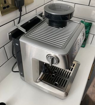 side view of the Ariete 1313 Espresso Machine on a white counter with white metro tile surround