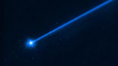 A Hubble telescope image of a bright blue asteroid, trailed by a long blue tail to the right. Small blue dots show boulders blasted away by NASA's DART mission.