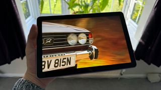 Amazon Fire HD 10 (2023) tablet held in hand showing car