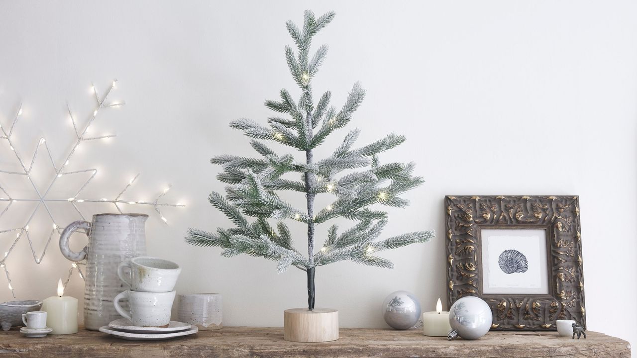 Small sparse christmas tree surrounded by other christmas decorations