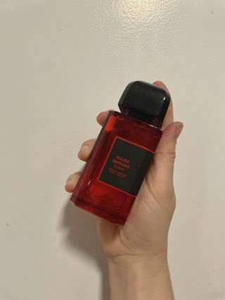 hand holding up BDK Parfums Rouge Smoking Extrait against beige wall