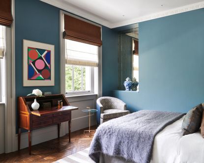 A teenage girl bedroom idea with blue walls, abstract art and antique writing desk