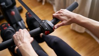 Echelon Row smart rowing machine handles showing two red buttons to adjust resistance up and down