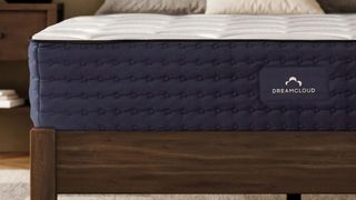 A close up of the end of the DreamCloud Hybrid mattress on a wooden bed frame