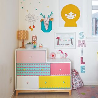 A kids' room with a patterned storage cupboard and colourful decor on the walls