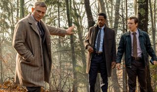 Daniel Craig signals for LaKeith Stanfield and Noah Segan to hold up in the woods in Knives Out.
