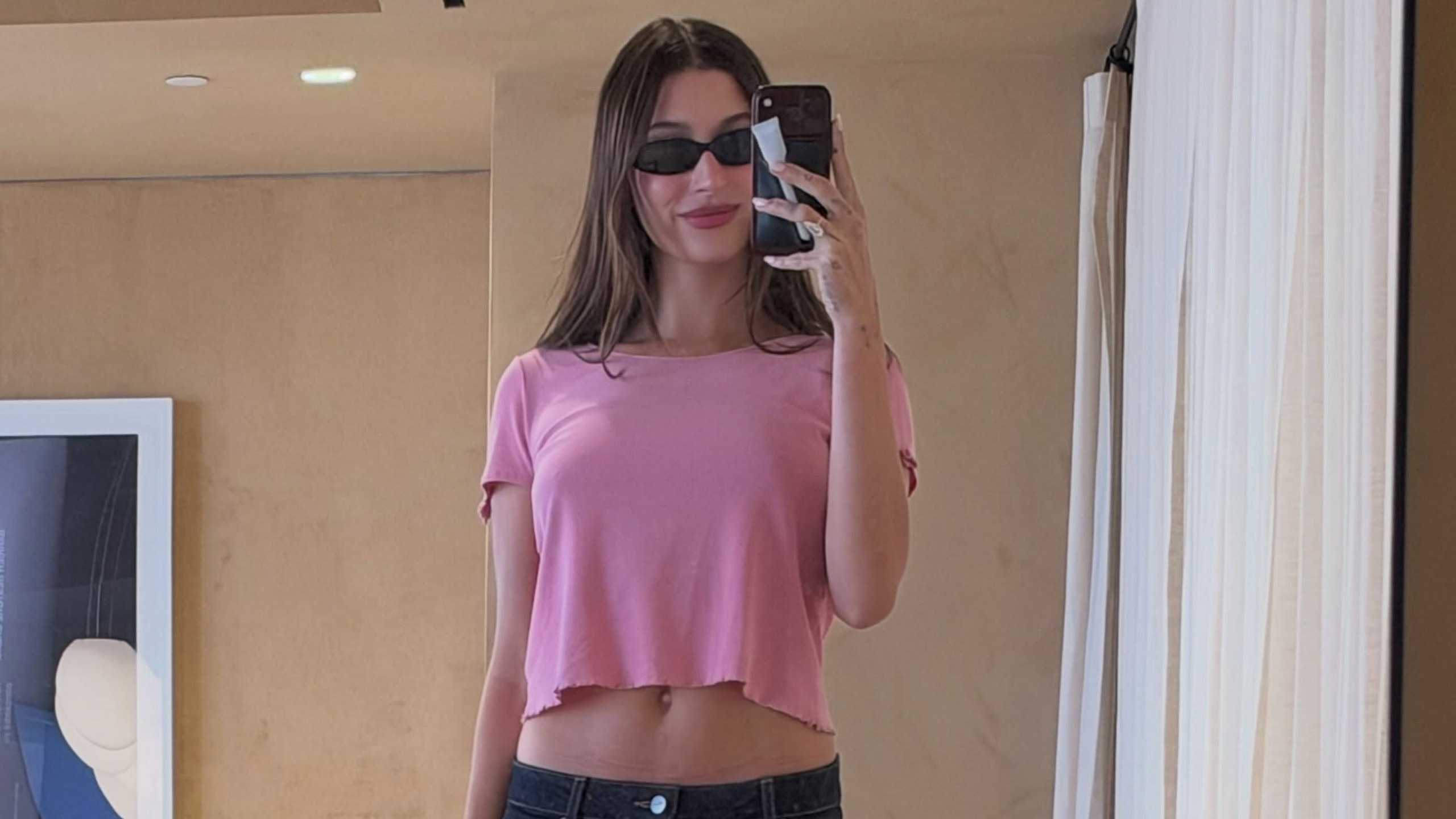 hailey wears a cropped pink tee and sunglasses.
