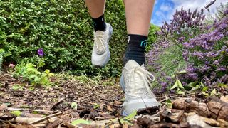 Person's feet on trail wearing NNormal Tomir trail running shoes