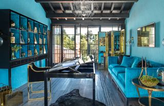 Turquoise living room in an artist's atelier designed by Timothy Corrigan, with black and gold furniture and accents.