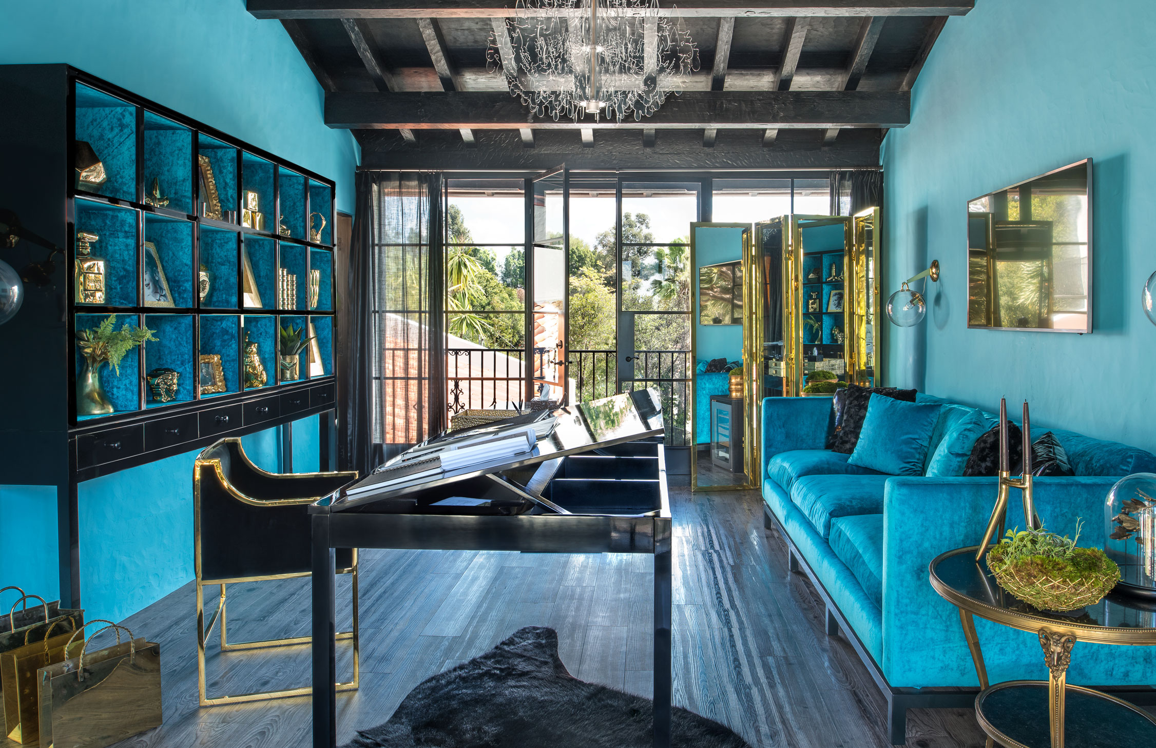 Turquoise living room in an artist's atelier designed by Timothy Corrigan, with black and gold furniture and accents.