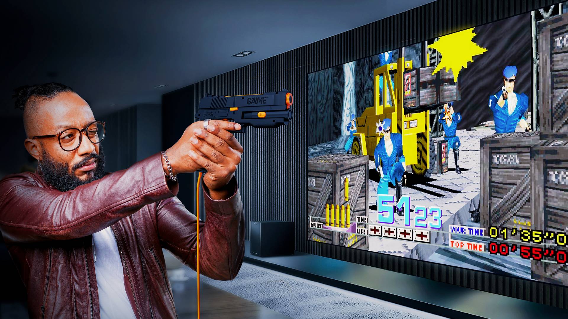 Masc presenting person holding G'AIM'E light gun in front of large screen featuring Time Crisis gameplay.
