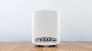 Netgear Orbi RBK353 on a wooden table in front of a white background