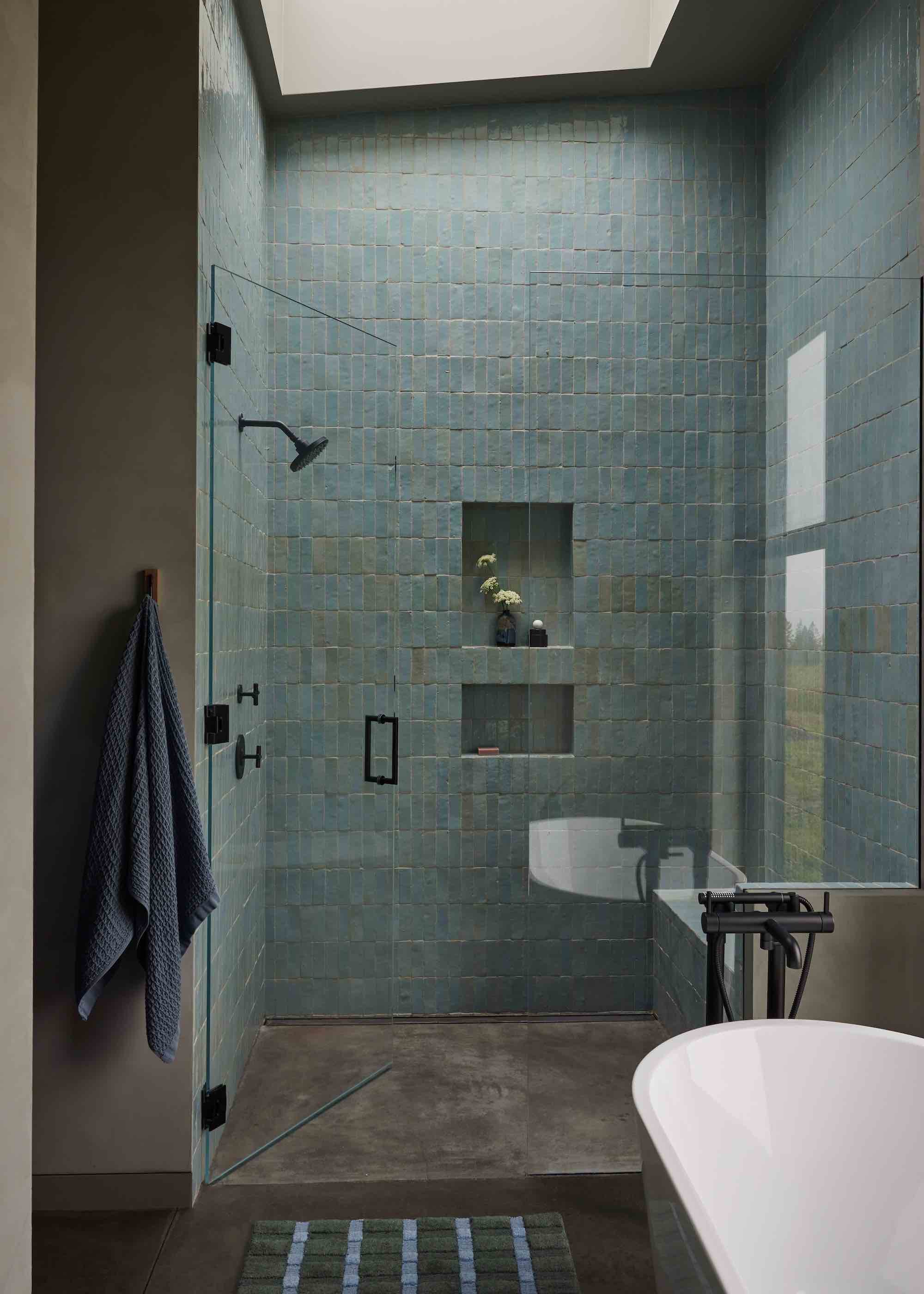 shower with blue tiles and skylight above as well as a bath tub in the space.