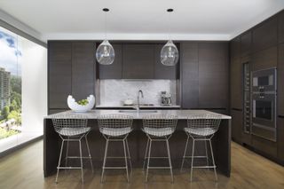 Kitchen with island and bar stools and pendant lights above and large backsplash