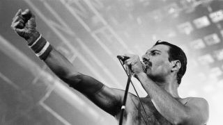 Freddie Mercury onstage with his fist held out in triumph