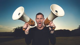 A press shot of Parkway Drive's Winston McCall holding two megaphones and shouting