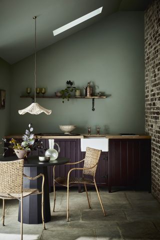 dark wood dining room kitchen with sage green wall and rattan pendant light