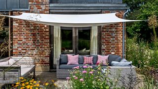 garden awning providing shade to a seating area but also blocking sunlight through windows as a way of how to cool down a room in summer