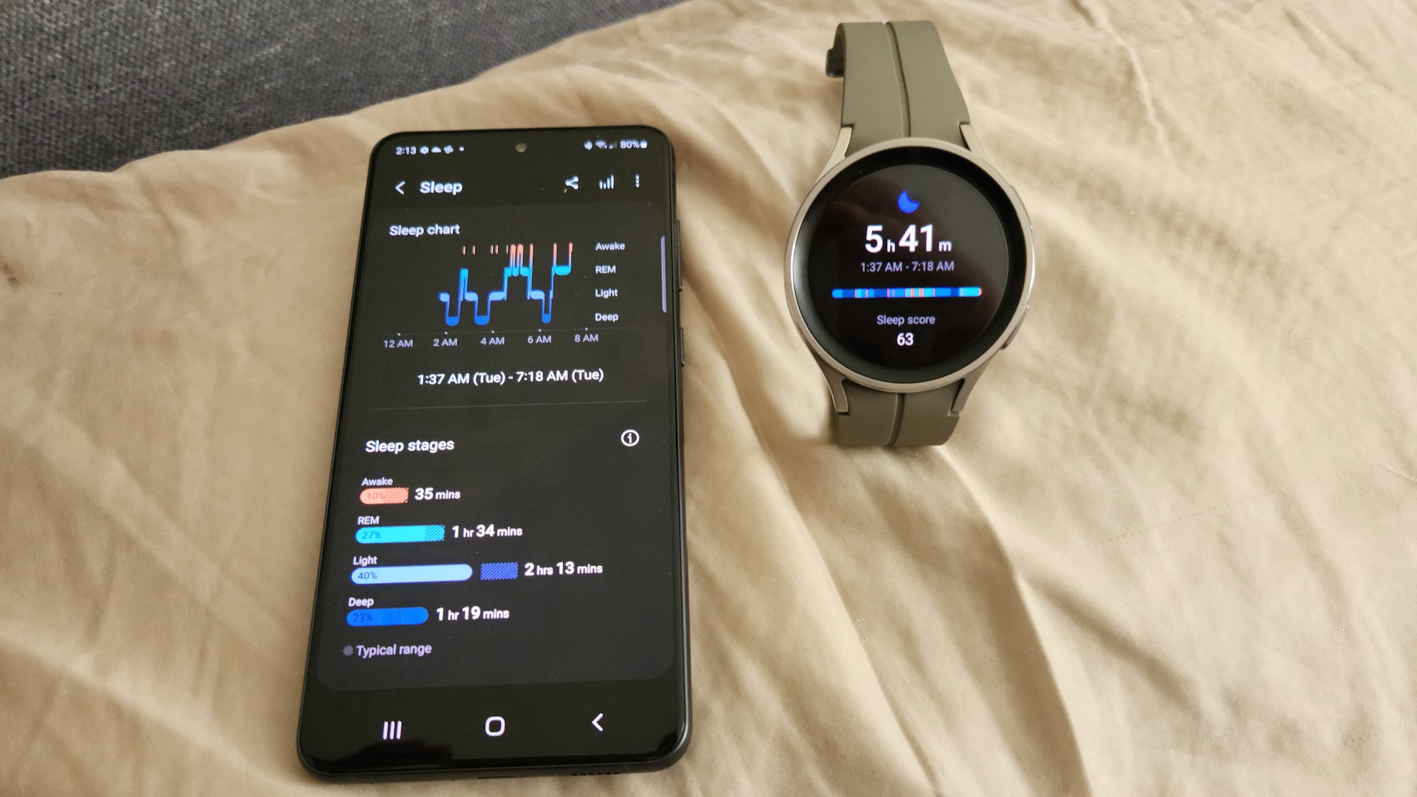 The Samsung Galaxy S21 FE and Samsung Galaxy Watch 5 Pro sitting on a pillow, showing sleep tracking results.