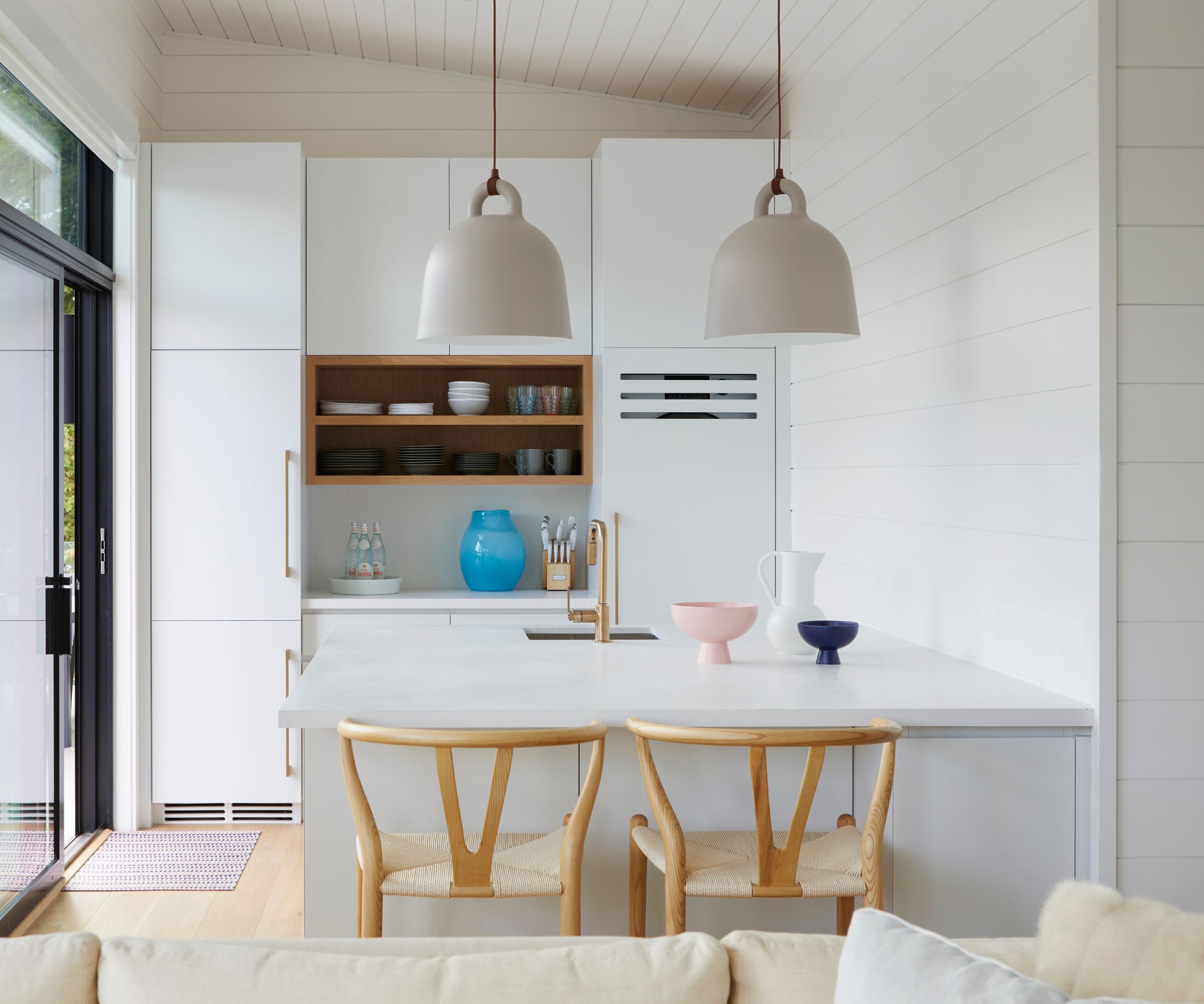 A small peninsula kitchen with walls and cabinets painted in Chantilly Lace by Benjamin Moore, paired with natural wood accents