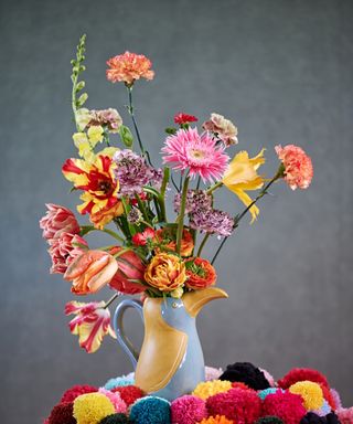 Blue and yellow jug with brightly colored tulips and ranunculus