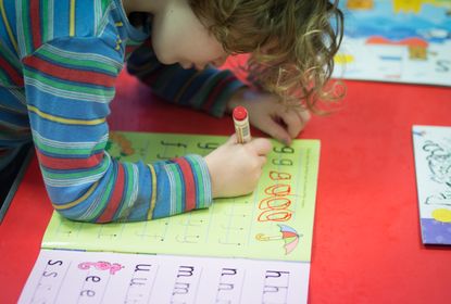A pre-school aged child practices lettering.
