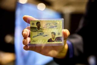 A person holding a Messi-Ronaldo Dual Auto 1/1 Superfractor Card, part of the Topps Chrome Set, which has captured the attention of collectors and enthusiasts worldwide. This card, featuring two of the greatest players of all-time is valued at an eye-watering £100,000