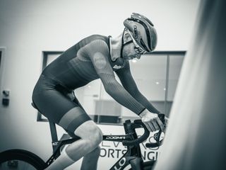 A black and white photo of Tom wearing the Abus Gamechanger helmet while riding in a wind tunnel