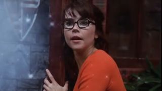 Linda Cardellini looks on in surprise as she holds a door in Scooby Doo.