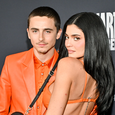 and man and a woman in orange outfits on a black backdrop
