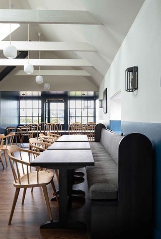 Interior of the Kinneuchar Inn, Fife, UK with blue and white walls, wooden chairs and tables and bench seats with grey cushions