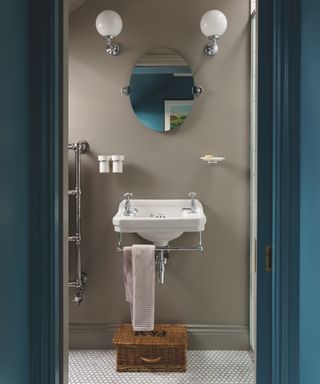 Small bathroom with stone gray walls, framed by teal woodwork door surround and door, mirror, white sanitaryware,