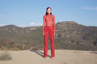 Woman in Ferragamo red sparkly top and trousers stands in Los Angeles canyon