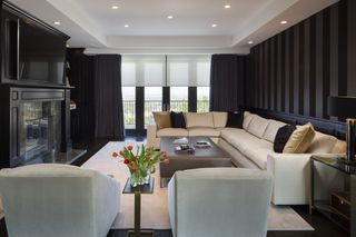 A TV room with striped black walks and cream furnishings