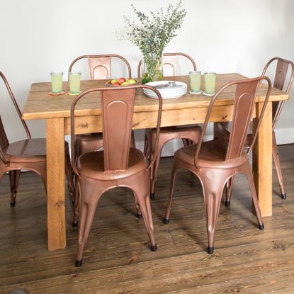A wooden dining table with a vase of flowers and metal chairs