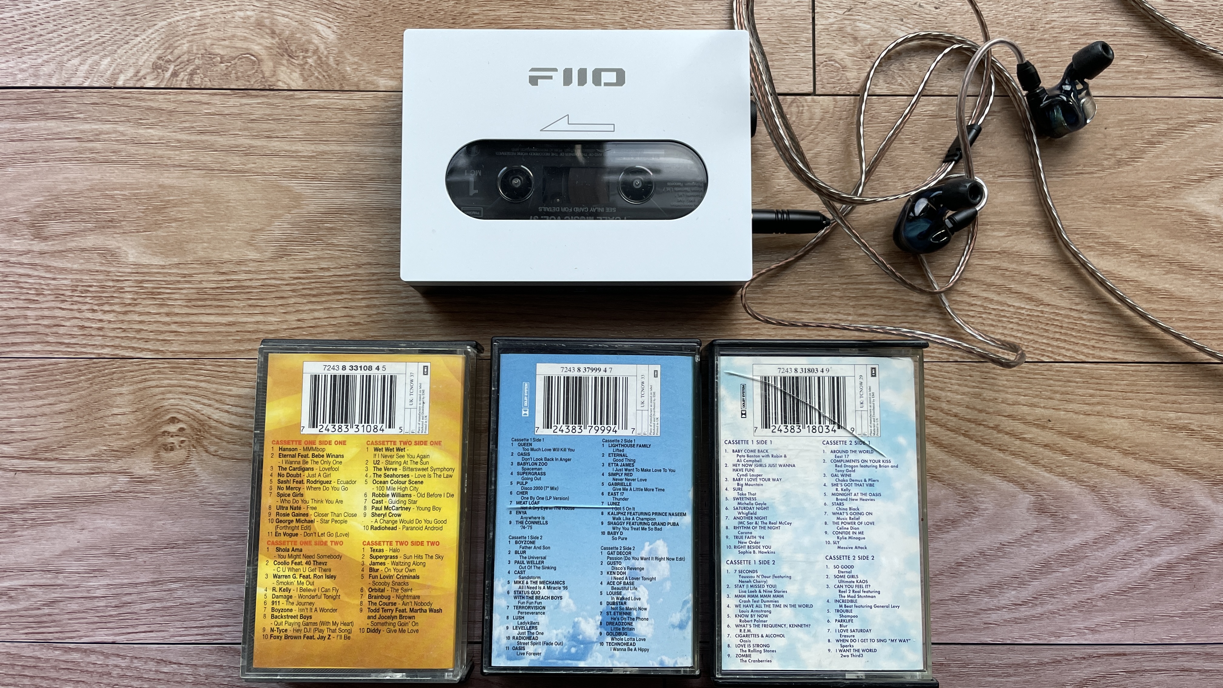 A selection of cassette tapes and a FiiO Walkman, on a wooden surface or held in a hand