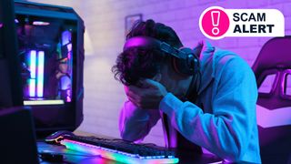 A man sitting in front of a PC with his head in his hands