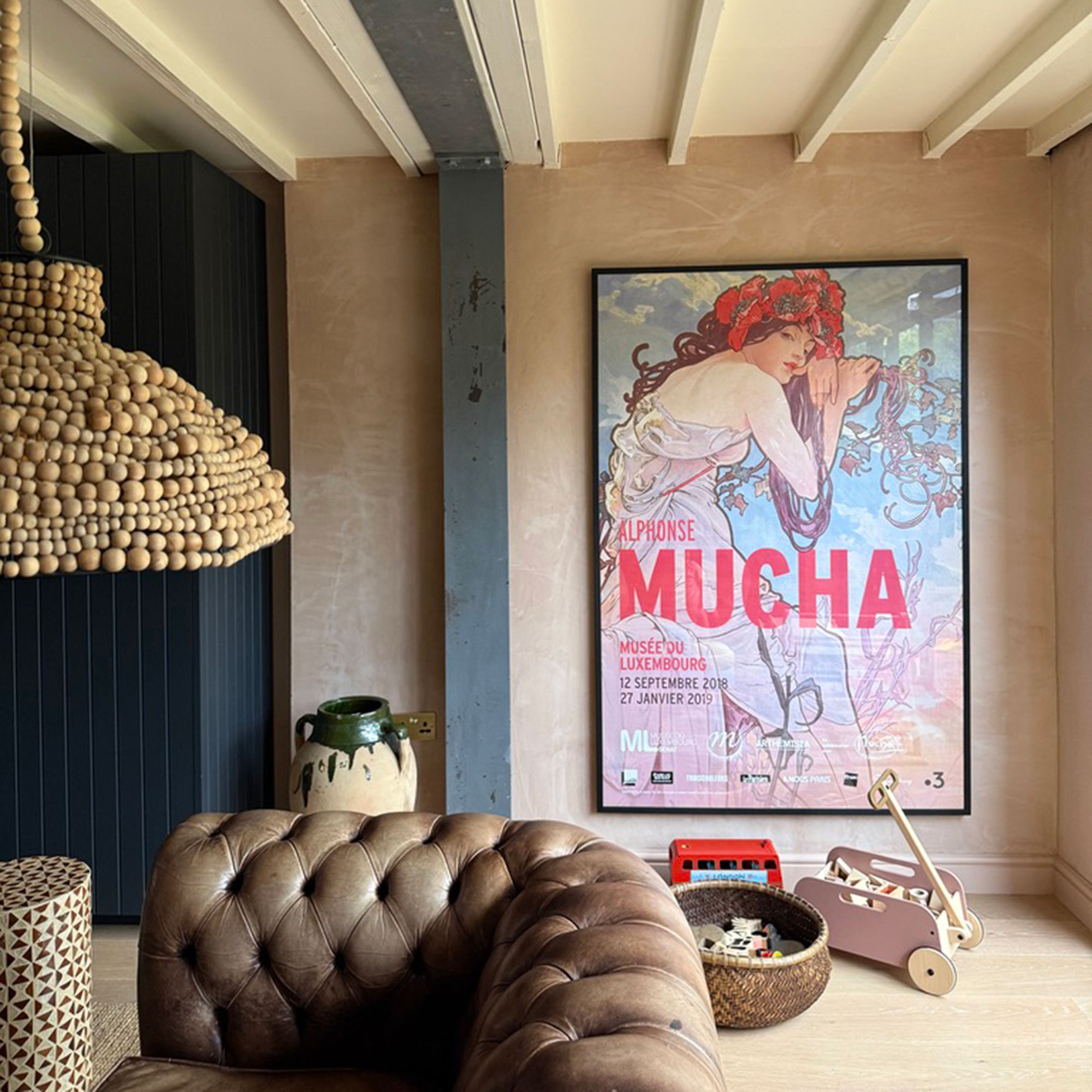 Living room with leather sofa, beams on ceiling and large poster on wall