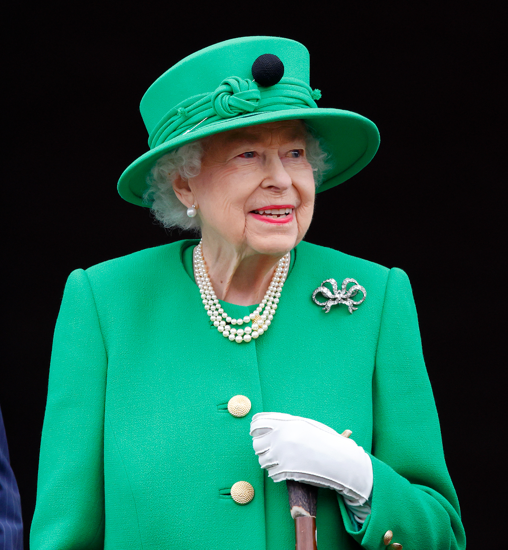 Queen Elizabeth wearing a green coat and hat with pearls