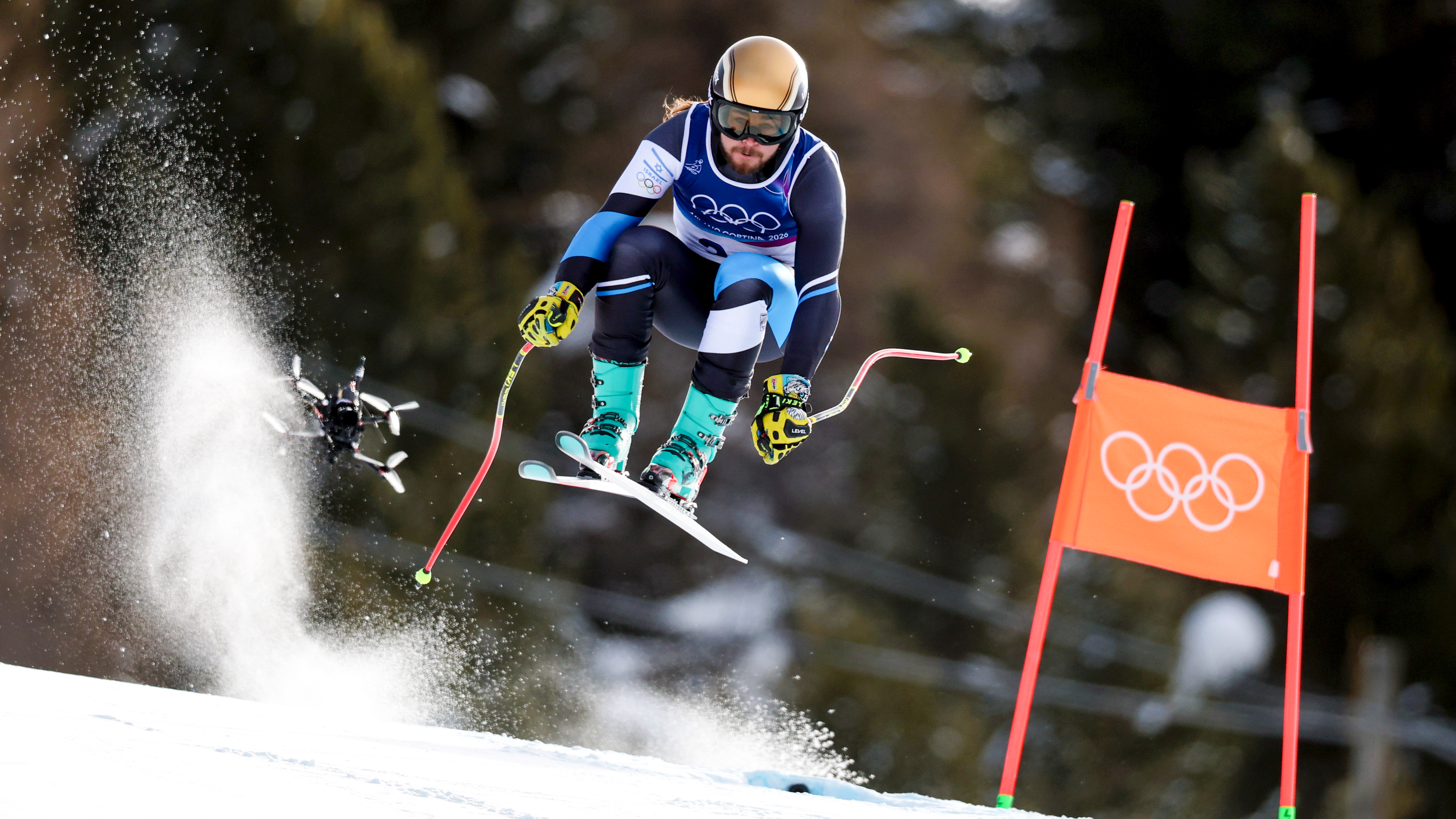 BORMIO, ITALY - FEBRUARY 07: Barnabas Szollos of Team Israel  skis as a drone follows him down the course during the Men's Downhill on day one of the Milano Cortina 2026 Winter Olympics at Stelvio Alpine Skiing Centre on February 07, 2026 in Bormio, Italy. (Photo by Dustin Satloff/Getty Images)