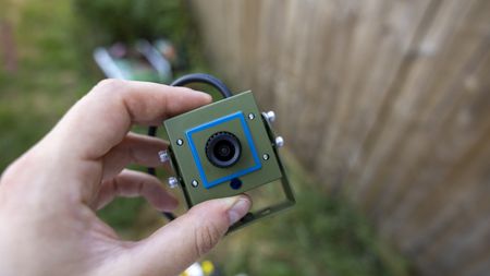 A female hand holding the Green Feathers bird box camera